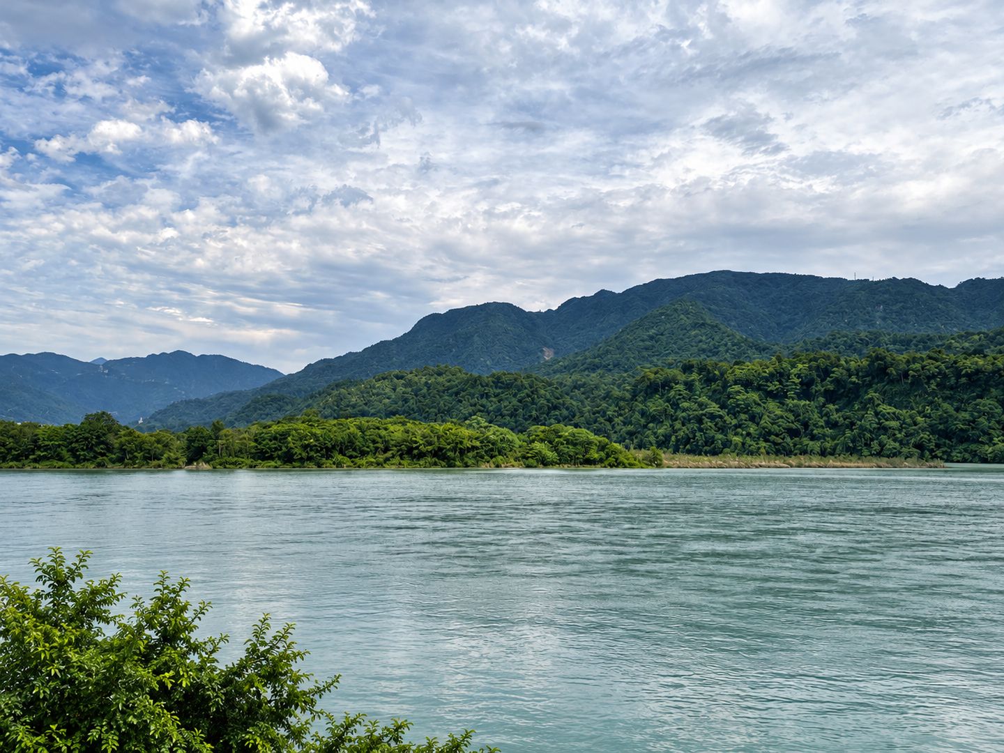 The Ganges and forested Himalayan foothills in Rishikesh; foreground buildings removed with AI retouching