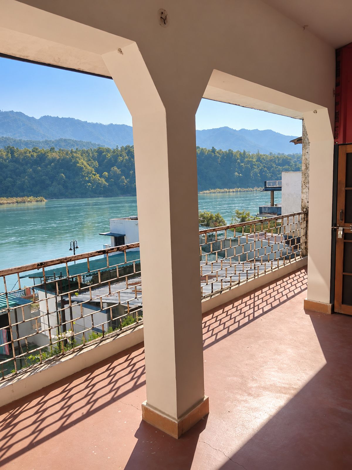 Sunlit Room 1 veranda with a railing overlooking the Ganges